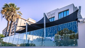 A hotel with a modern facade, a prominent sign reading "Sugar Hotel," and a large glass window reflecting the surroundings. - Sugar Hotel (Cape Town)