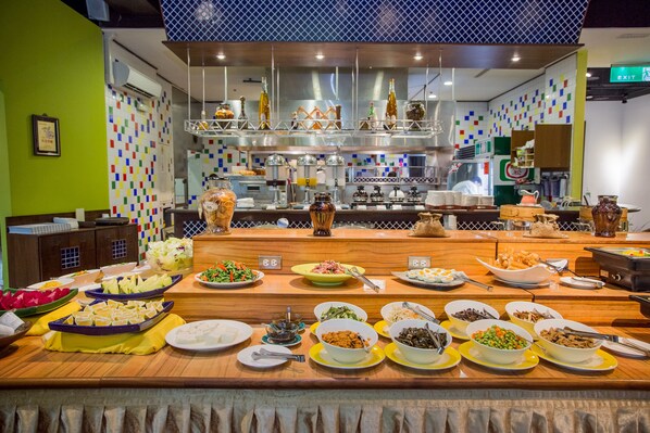 A buffet with various dishes and a kitchen area in the background.