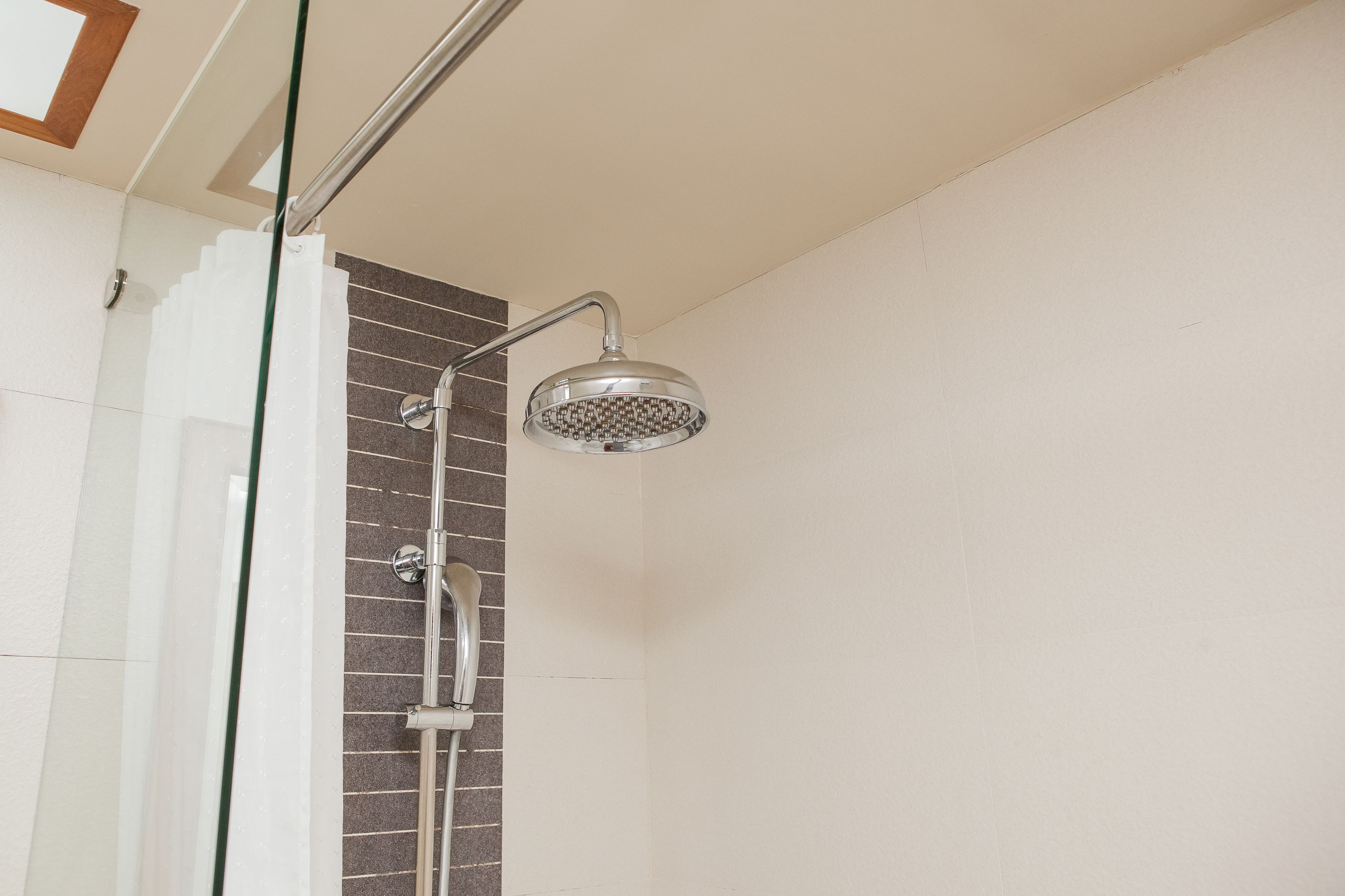 A shower with a glass door and a tiled wall.
