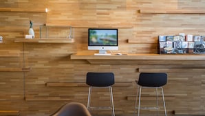 A modern reception desk with a computer monitor, two black bar stools, and a display of books. - Jiuwu Hotel (Luodong)