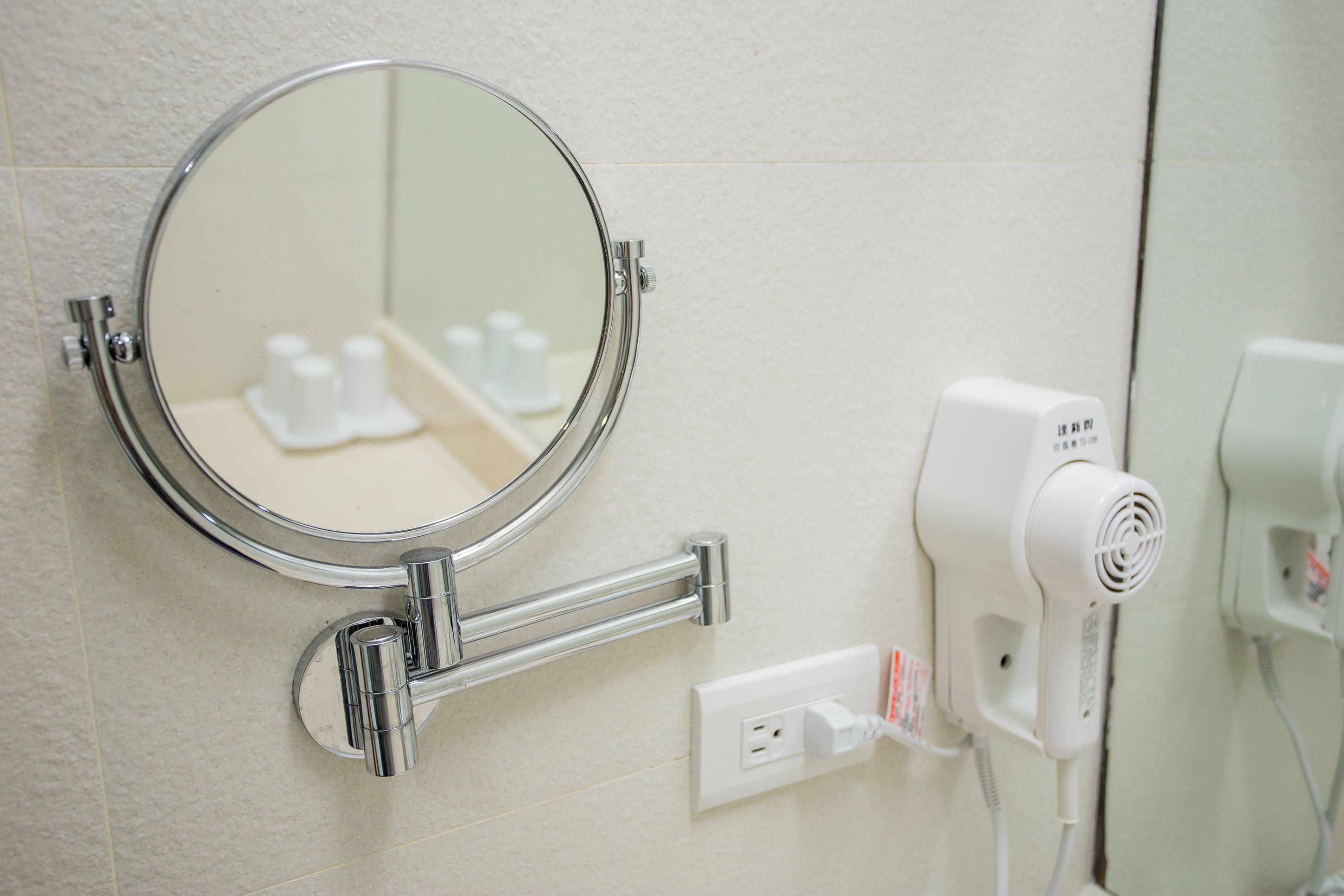 Une salle de bain avec un miroir rond, un sèche-cheveux et un lavabo.