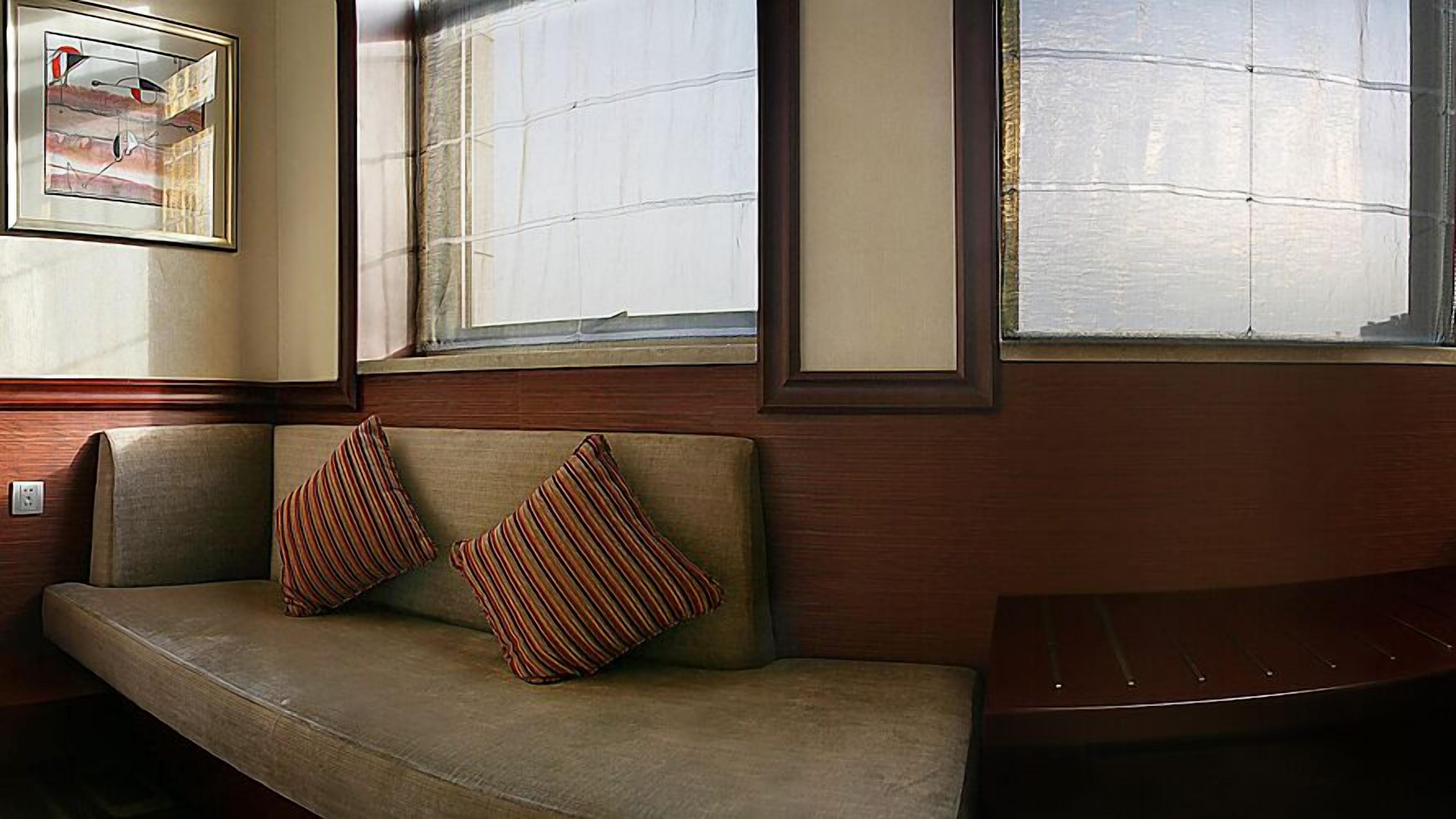 A room with a wooden bench, a cushioned bench with striped pillows, and a framed picture on the wall.