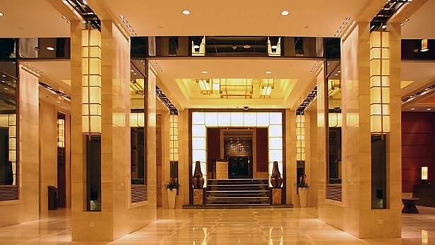 A spacious lobby with a central staircase, large columns, and a modern chandelier. - Beijing Minzu Hotel    (Beijing)