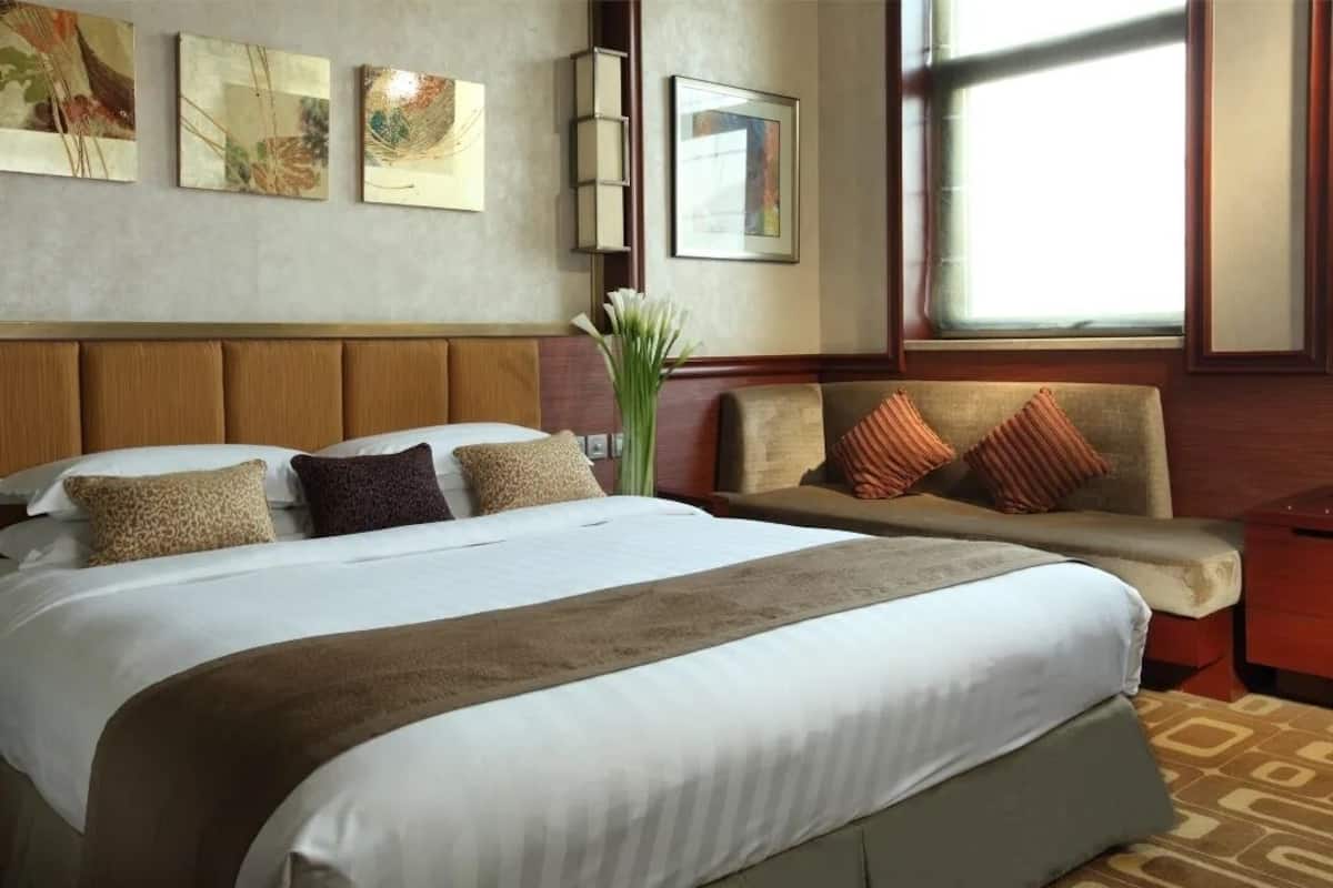 Une chambre d’hôtel avec un grand lit, un canapé et une fenêtre donnant sur un beau paysage.
