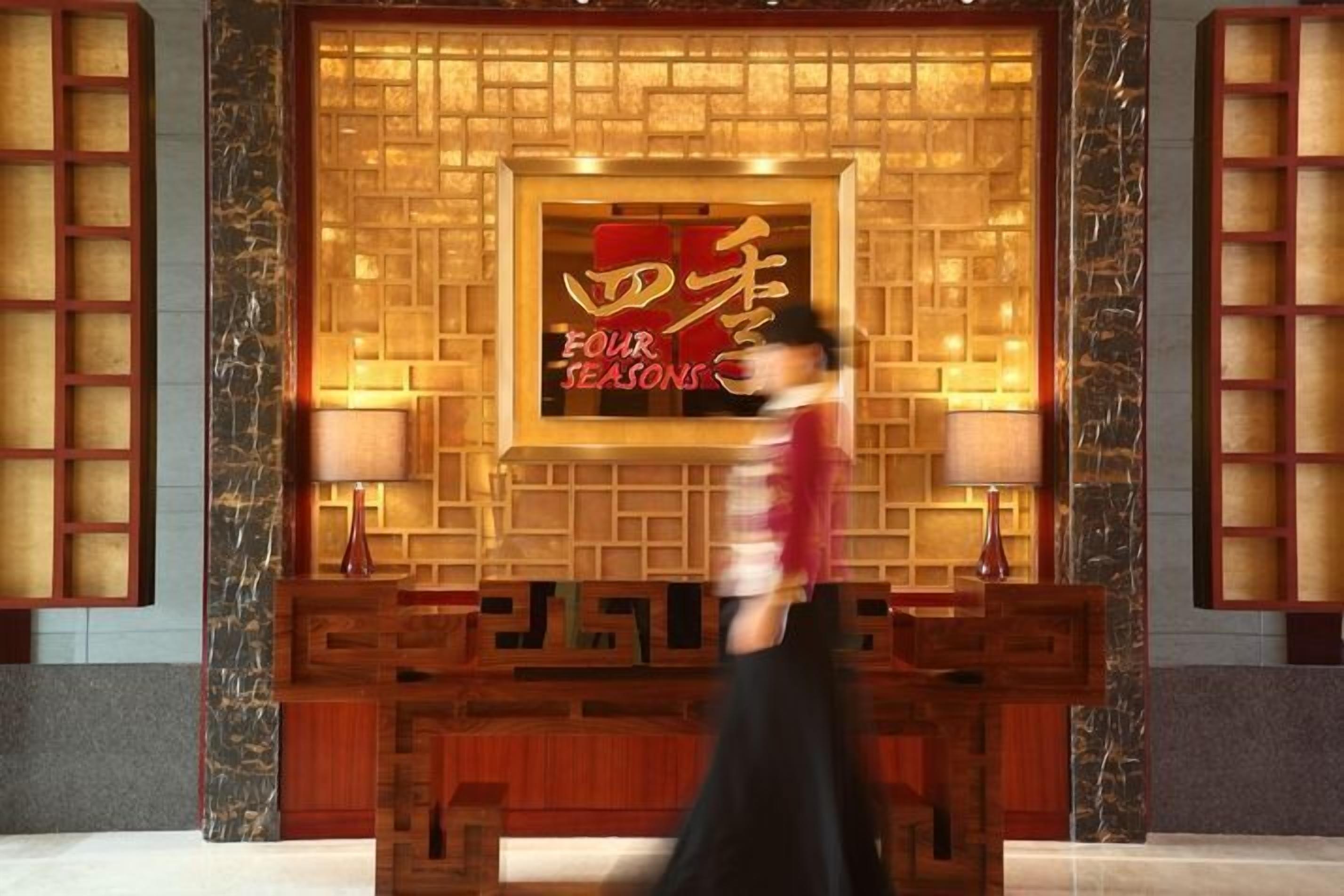 A hotel entrance with a traditional design, featuring a wooden reception desk and a sign that reads "Four Seasons."