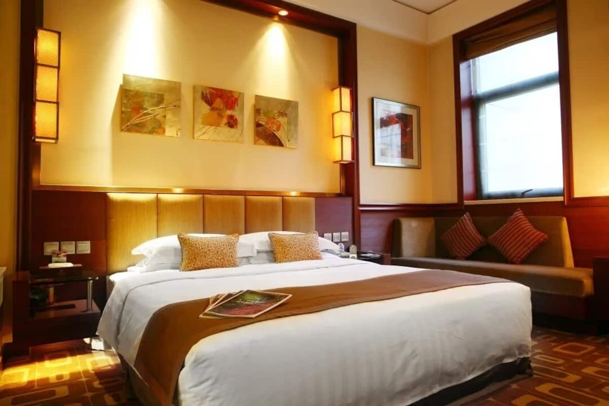 Une chambre d’hôtel avec un grand lit, un canapé et une fenêtre donnant sur un beau paysage.