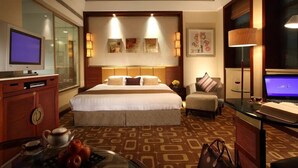 A hotel room with a large bed, a desk with a laptop, a television, and a coffee table with apples. - Beijing Minzu Hotel    (Beijing)