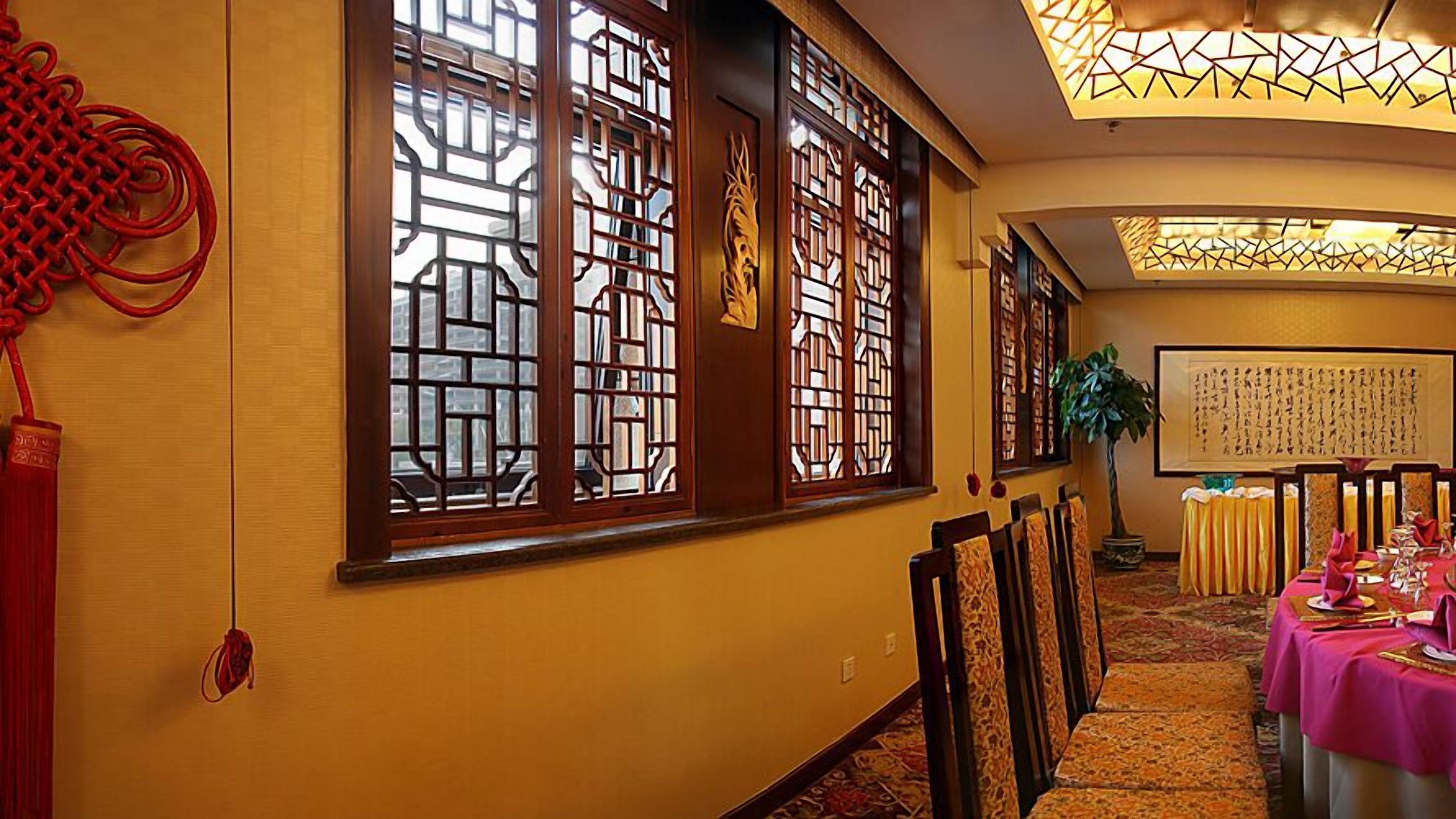A traditional room with wooden sliding doors, a dining area with tables set for a meal, and a large calligraphy artwork on the wall.