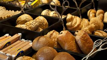 Una vitrina de panadería con diversos productos horneados, como pan, bollos y pasteles.