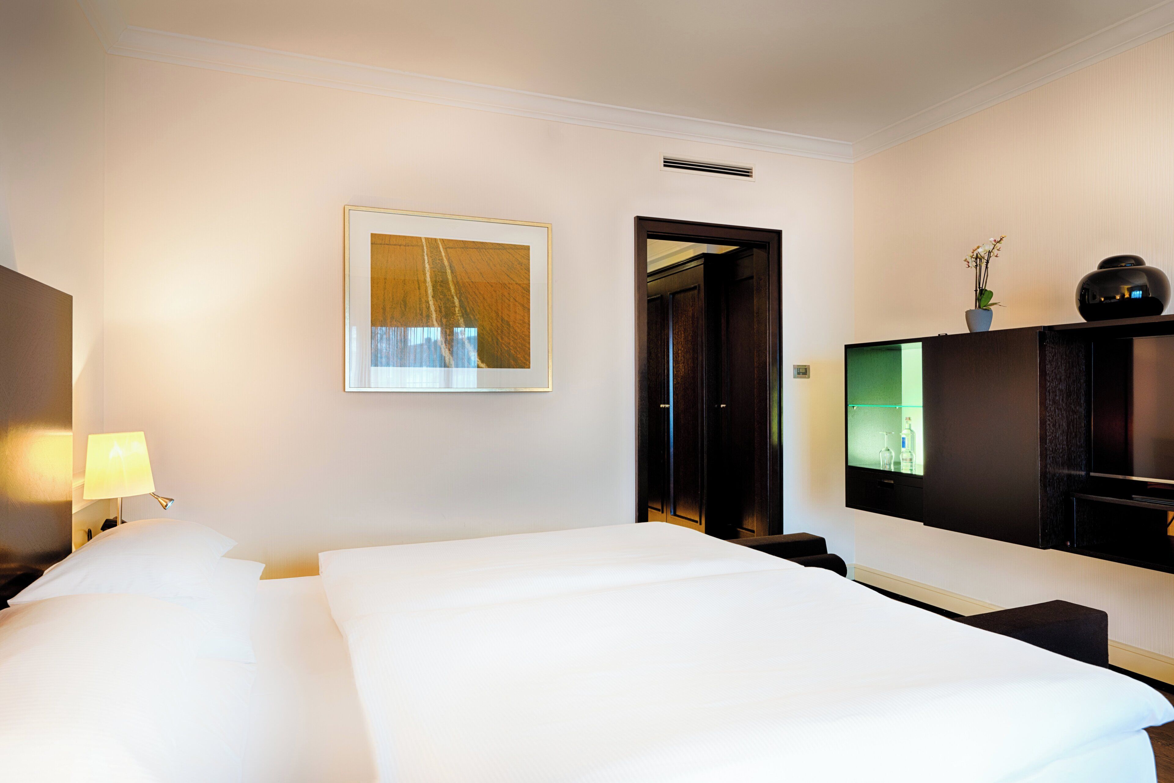 Habitación de hotel con cama, escritorio, televisor y un cuadro en la pared.