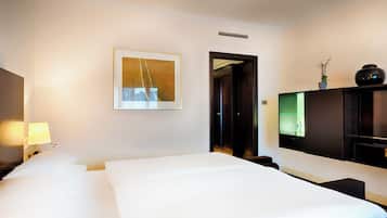 Habitación de hotel con cama, escritorio, televisor y un cuadro en la pared.