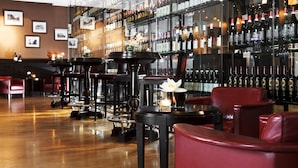 A bar area with multiple tables and chairs, a wine display, and framed pictures on the wall. - Welcome Parkhotel Euskirchen (Euskirchen)