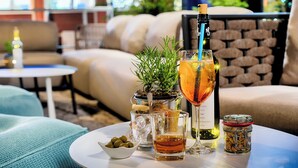 A table with a bottle of wine, a glass with a straw, a small bowl of olives, and a jar of nuts. - Welcome Parkhotel Euskirchen (Euskirchen)