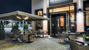 An outdoor seating area with tables and chairs, a covered section, and potted plants. - Welcome Parkhotel Euskirchen (Euskirchen)