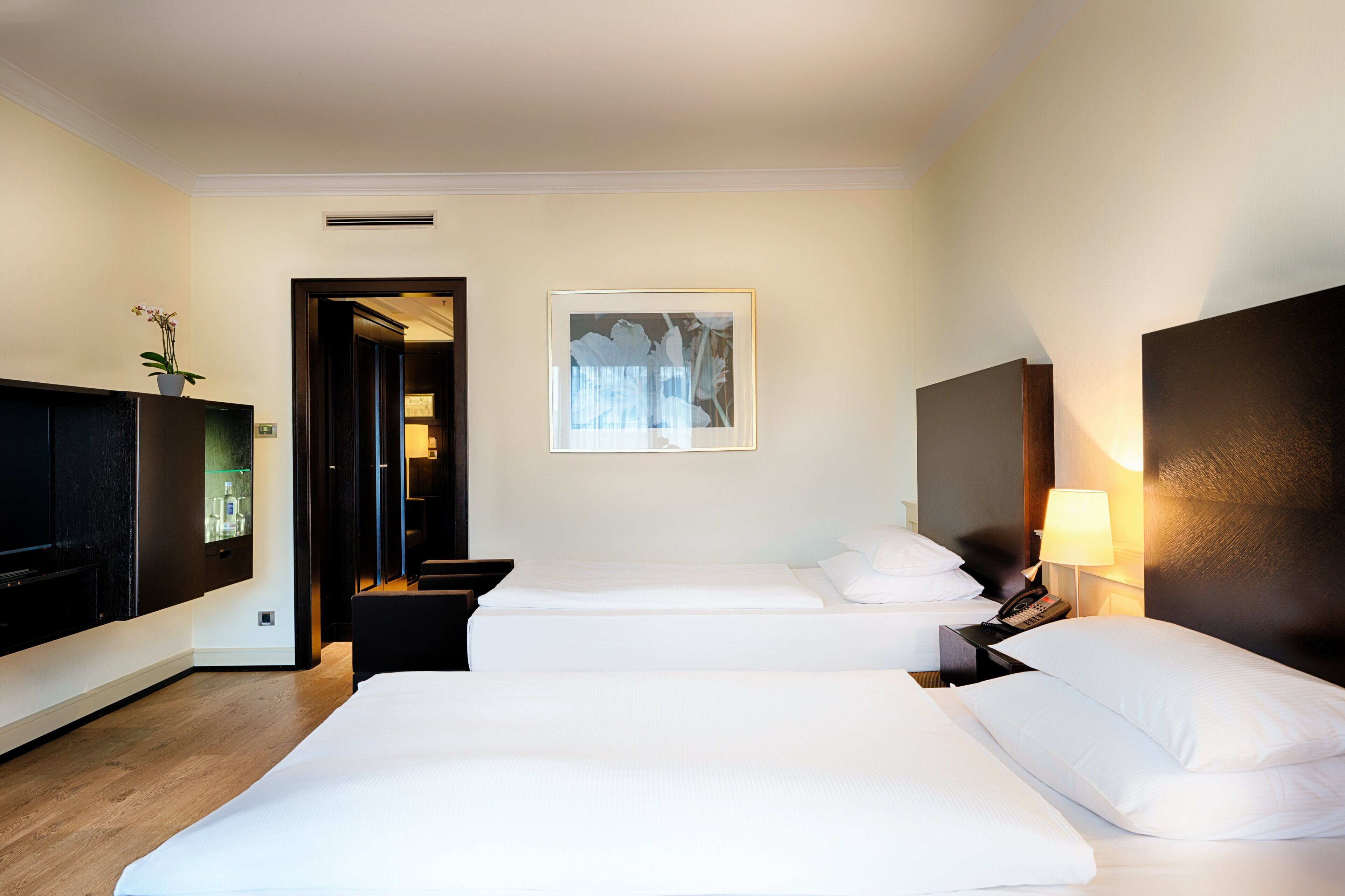 Habitación de hotel con dos camas, un televisor de pantalla plana, un escritorio y un cuadro en la pared.