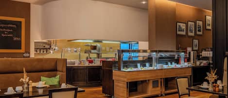 A restaurant with a counter, seating area, and a kitchen in the background.