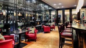 A modern bar area with glass partitions, red seating, and a variety of bottles. - Welcome Parkhotel Euskirchen (Euskirchen)