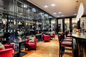 A modern bar area with glass partitions, red seating, and a variety of bottles.