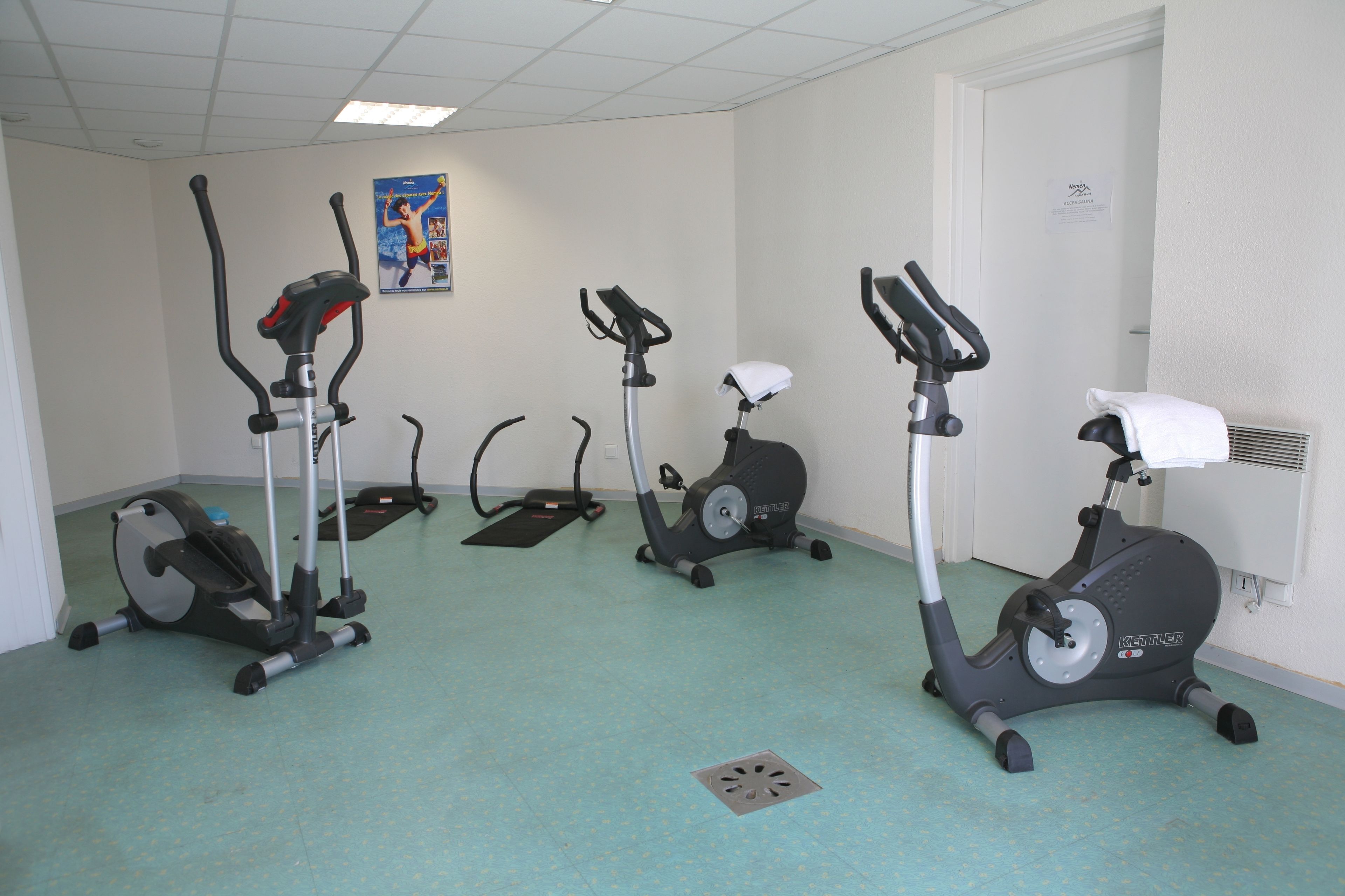 A fitness room with three stationary bikes and a treadmill.