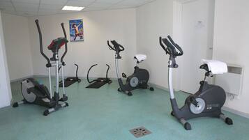 A fitness room with three stationary bikes and a treadmill.
