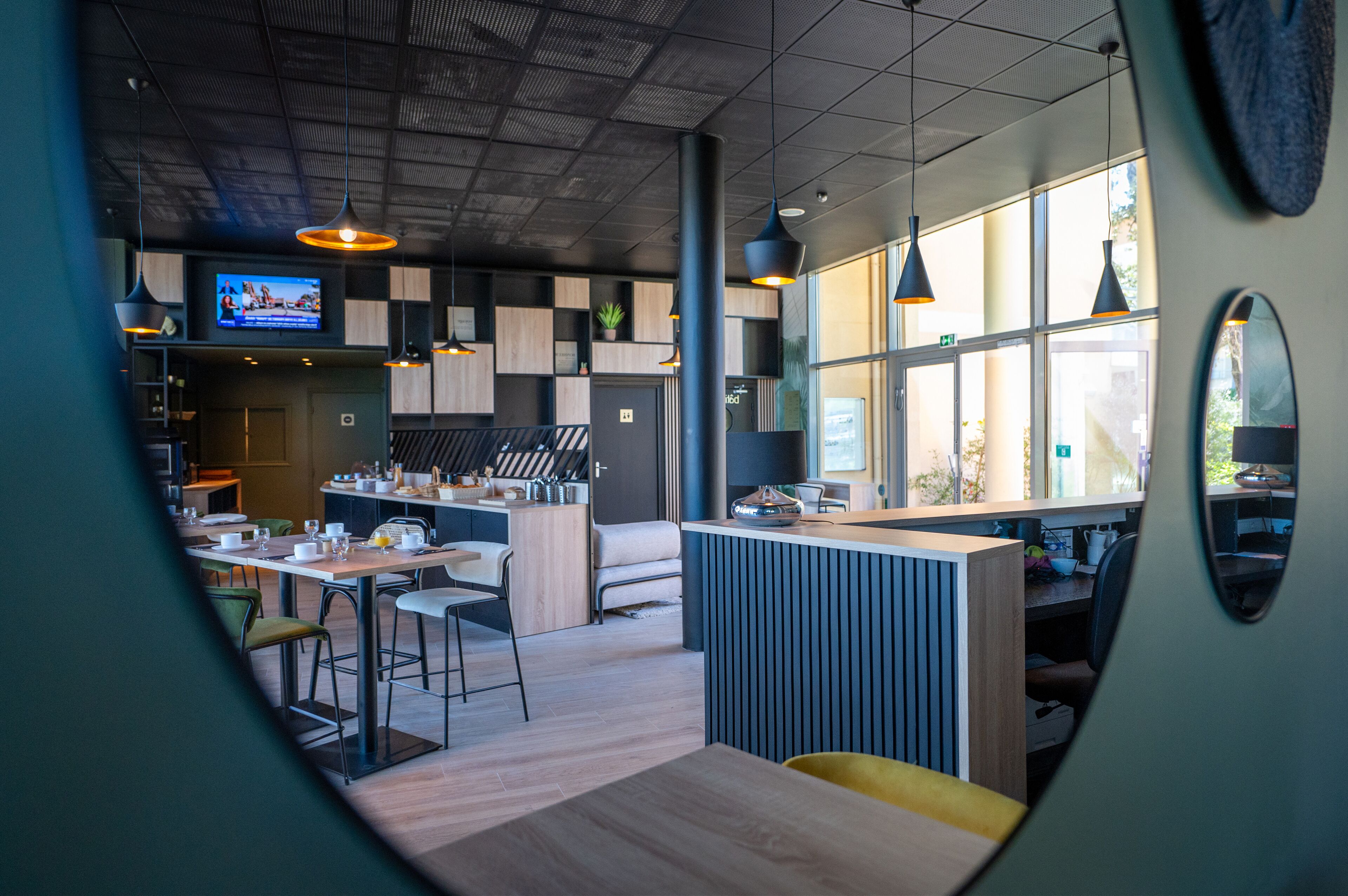 A modern restaurant with a kitchen area, dining tables, and pendant lighting.