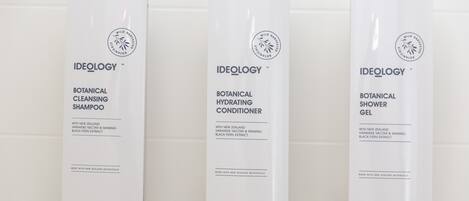 Three bottles of Ideology products: Botanical Cleansing Shampoo, Botanical Hydrating Conditioner, and Botanical Shower Gel.