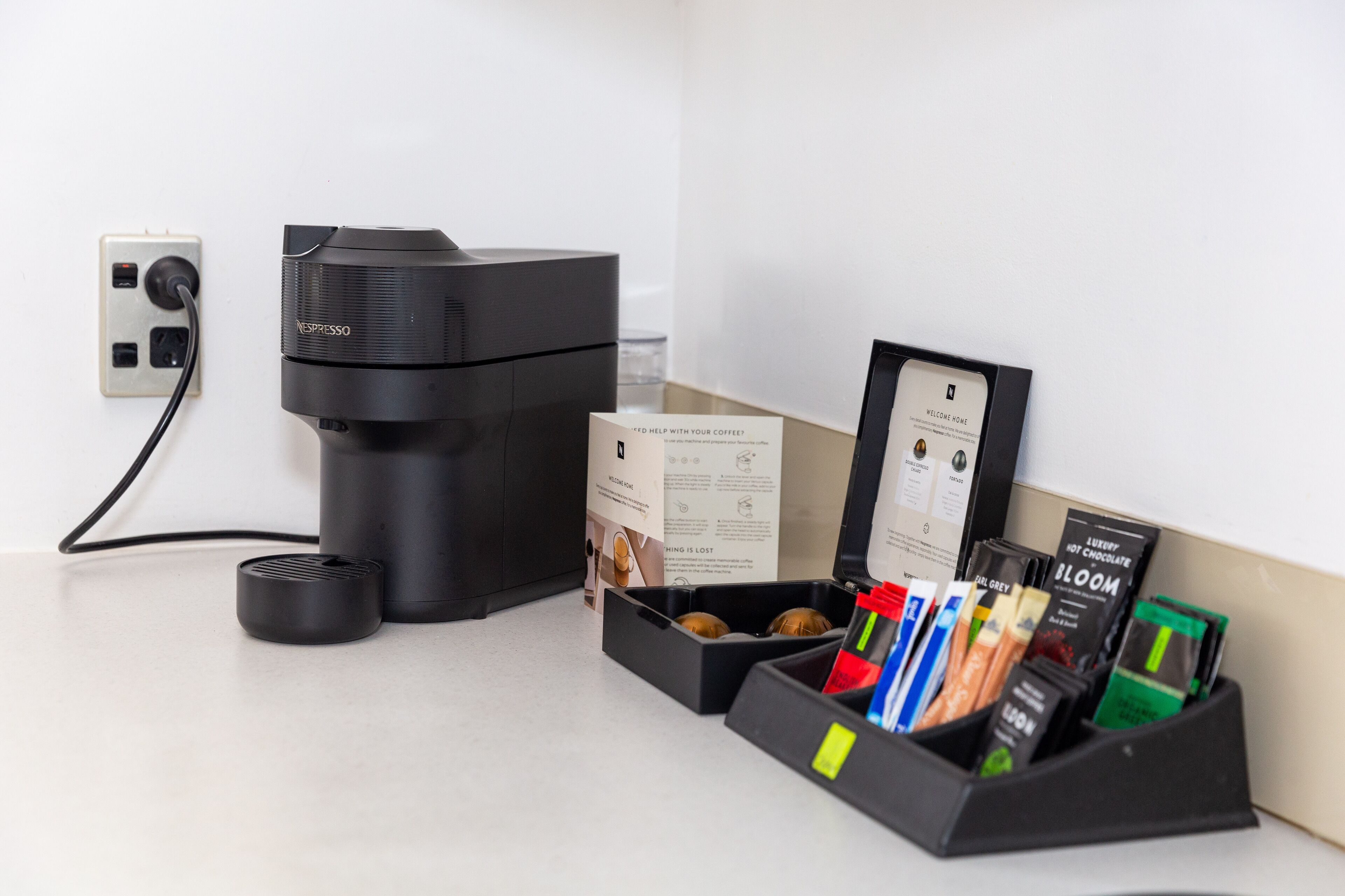 A Nespresso coffee machine, a coffee pod holder with various pods, and a welcome card.