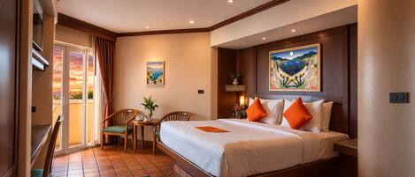 A hotel room with a bed, a desk, a chair, a small table, a plant, and a painting on the wall.