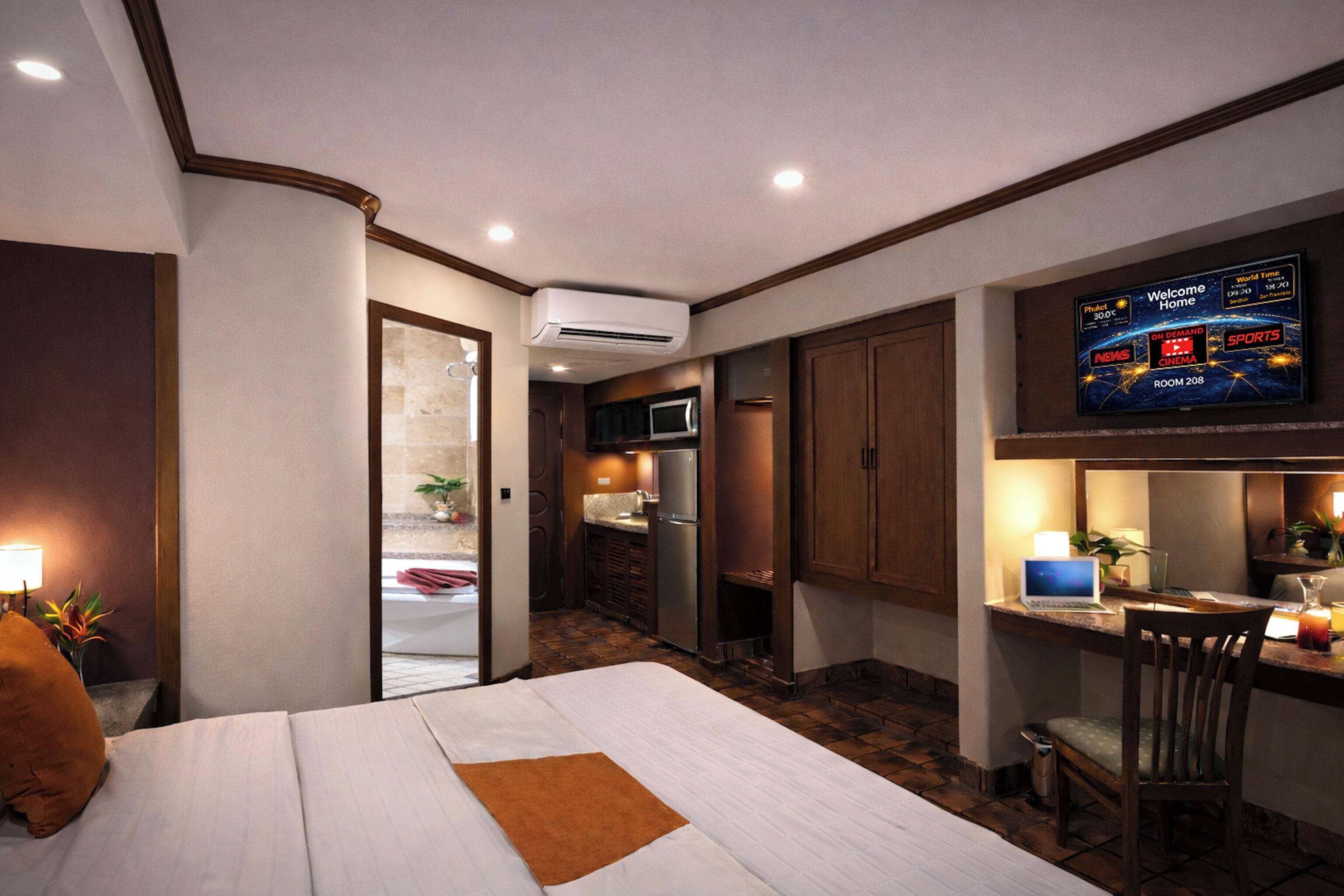 Una habitación de hotel con cama, un escritorio con silla, televisor y kitchenette.