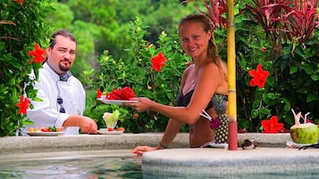 Enjoy a leisurely meal by the pool, surrounded by lush greenery.