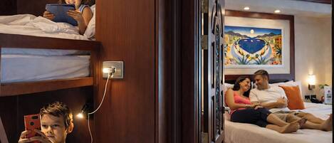 A hotel room with bunk beds, a bedside table, a wall-mounted light, and a painting.