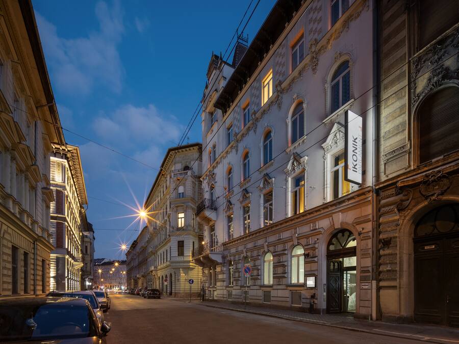 Vista de una calle con un edificio histórico de arquitectura ornamentada, cielo despejado y automóviles estacionados.