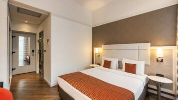 Habitación de hotel con una cama grande, dos mesitas de noche, un espejo y un diseño de pared moderno.