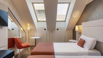 Una habitación de hotel con tragaluces, una cama, un escritorio y una silla.
