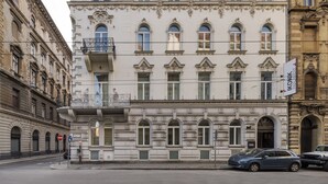 A historic building with ornate architectural details, multiple windows, and a sign indicating a business. - Ikonik Parlament (Budapest)