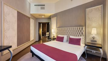 A hotel room with a large bed, a nightstand with a lamp, and a view of the hallway.