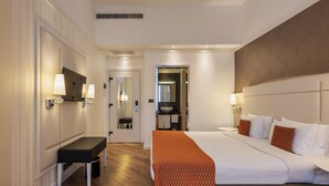 A modern hotel room with a large bed, a bench, a TV, and a bathroom visible through an open door. - Ikonik Parlament (Budapest)