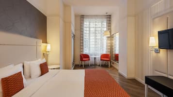 Une chambre d’hôtel avec un grand lit, deux lampes de chevet, une télévision, un bureau et une chaise.