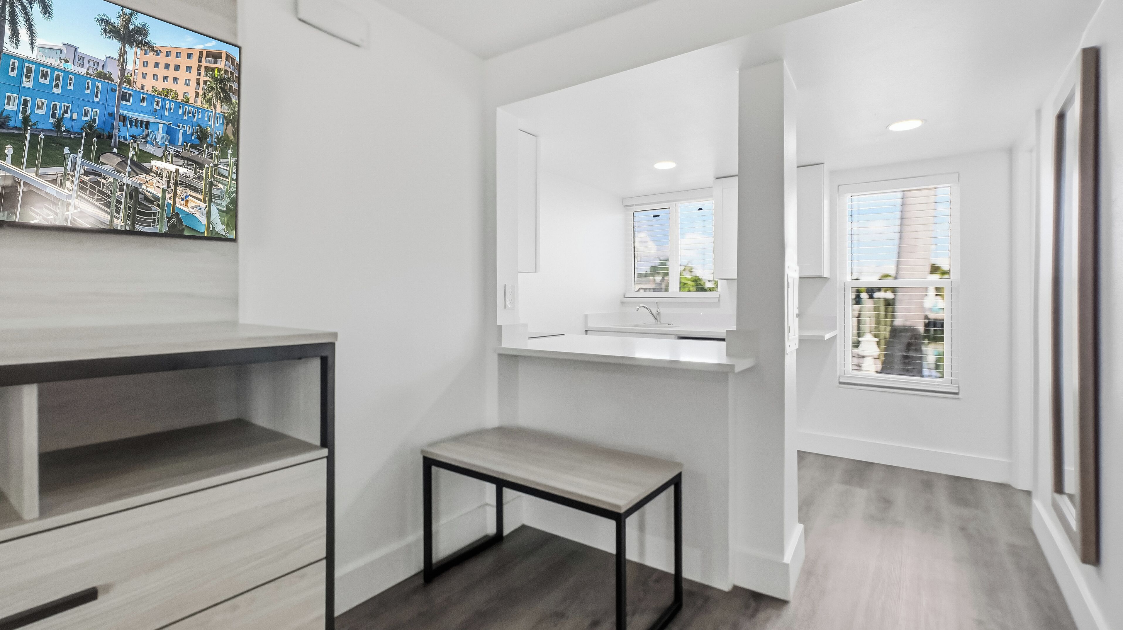 A modern bathroom with a white vanity, a small table, and a window with blinds.