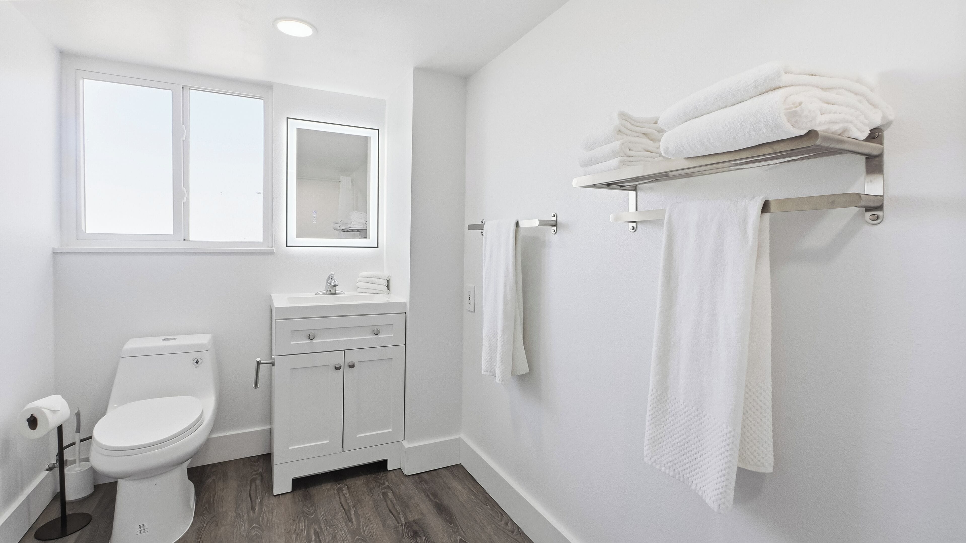 A modern bathroom with a toilet, sink, and towel rack.