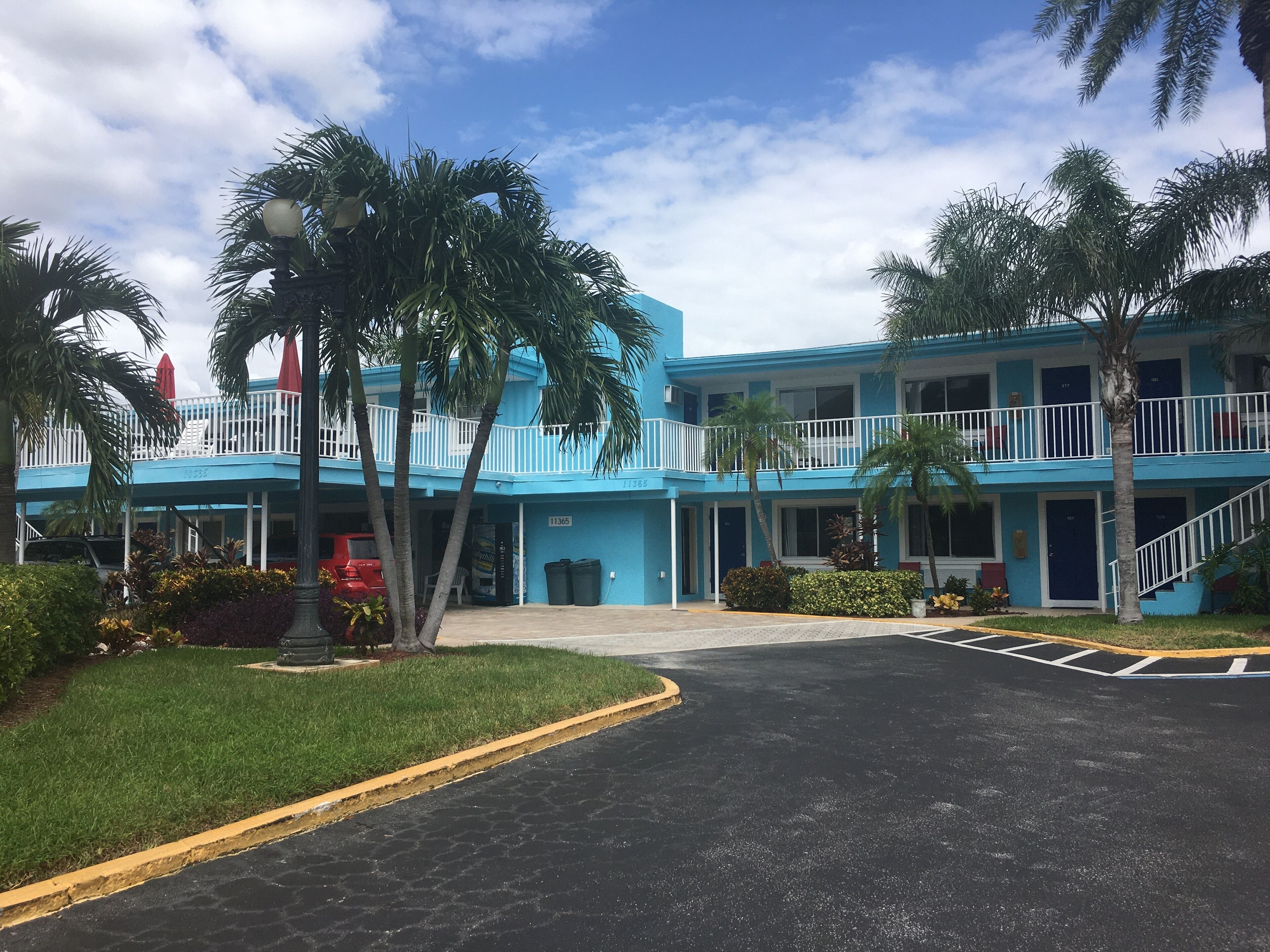 A two-story hotel with a blue exterior, a covered entrance, and a parking area.