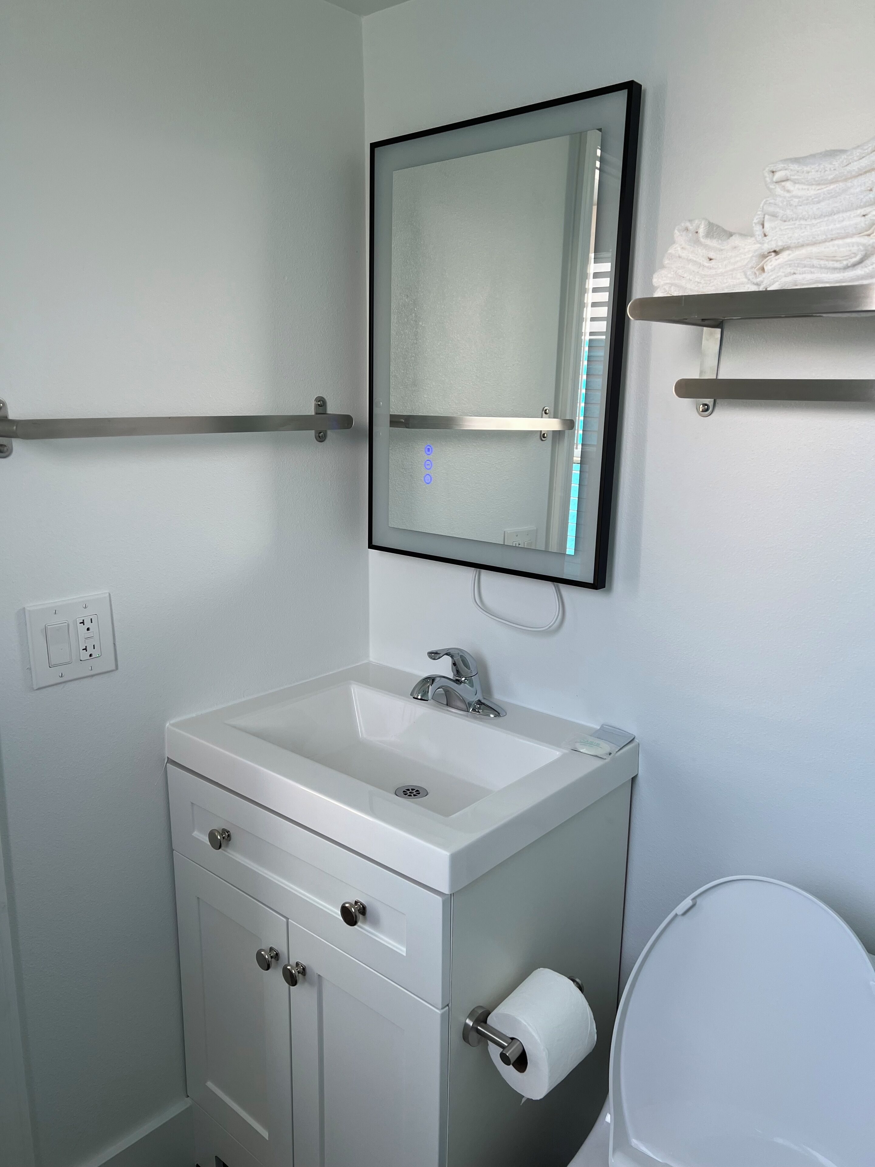 A bathroom with a white sink, a mirror, a toilet, and a towel rack.