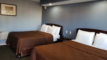 A hotel room with two beds, a nightstand, a framed picture on the wall, and an air conditioning unit.