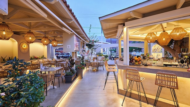 An outdoor café with tables and chairs, surrounded by potted plants and decorative lighting. - Mila Malia Studios Hotel  (Hersonissos)