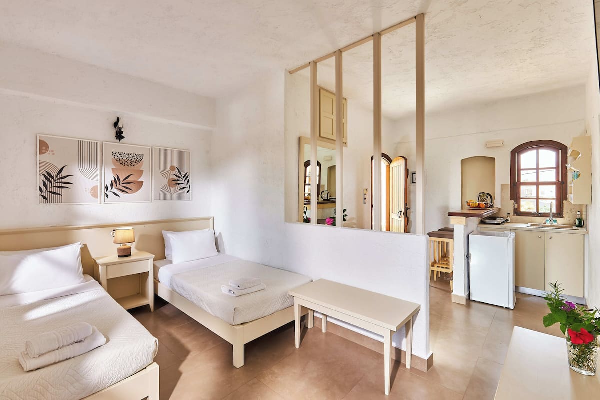 Een hotelkamer met twee bedden, een tafeltje, een spiegel en een kitchenette.
