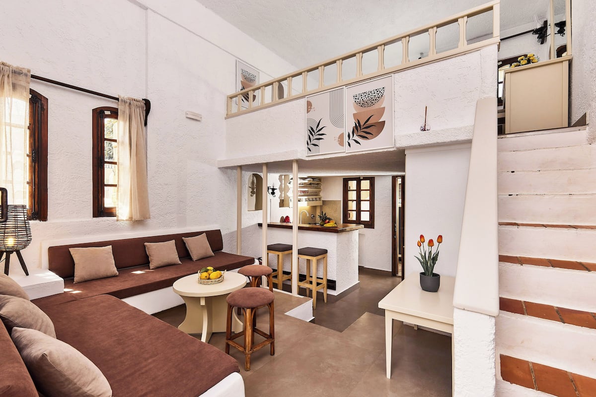 Een ruime woonkamer met een bank, een eettafel en een keuken met barkrukken.