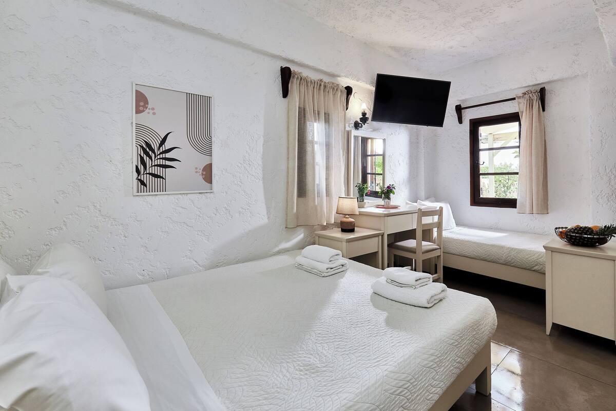 Hotelkamer met twee bedden, een bureau, een stoel, een televisie en een raam met gordijnen.