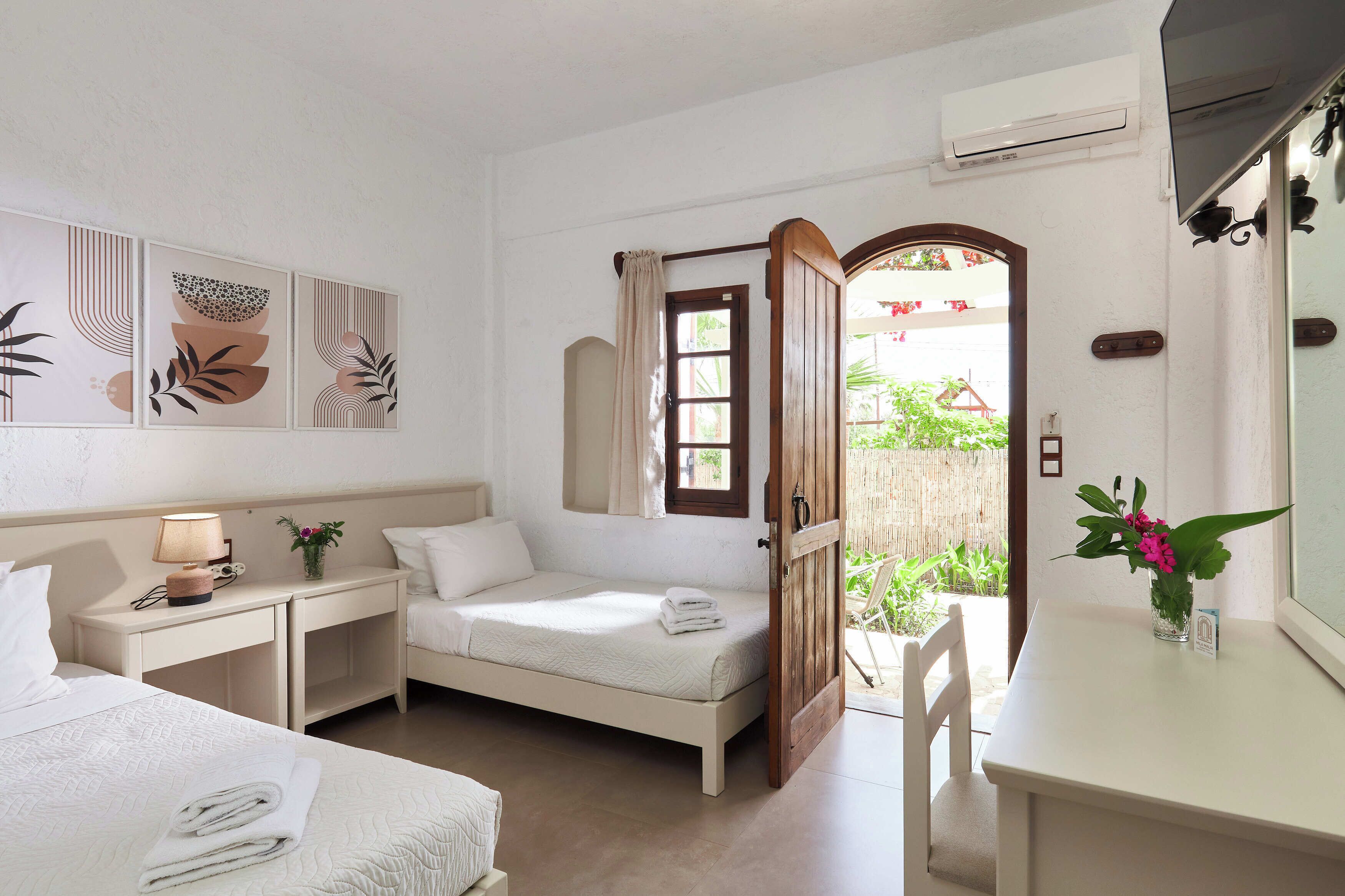 Una habitación de hotel con cama, escritorio, silla, una mesita y ventana con cortinas.