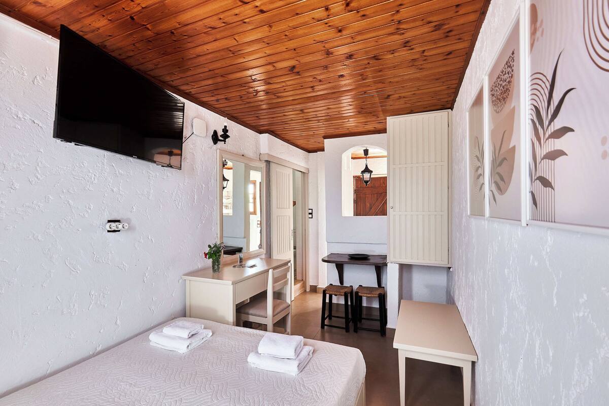 Een slaapkamer met een bed, een bureau en een spiegel.