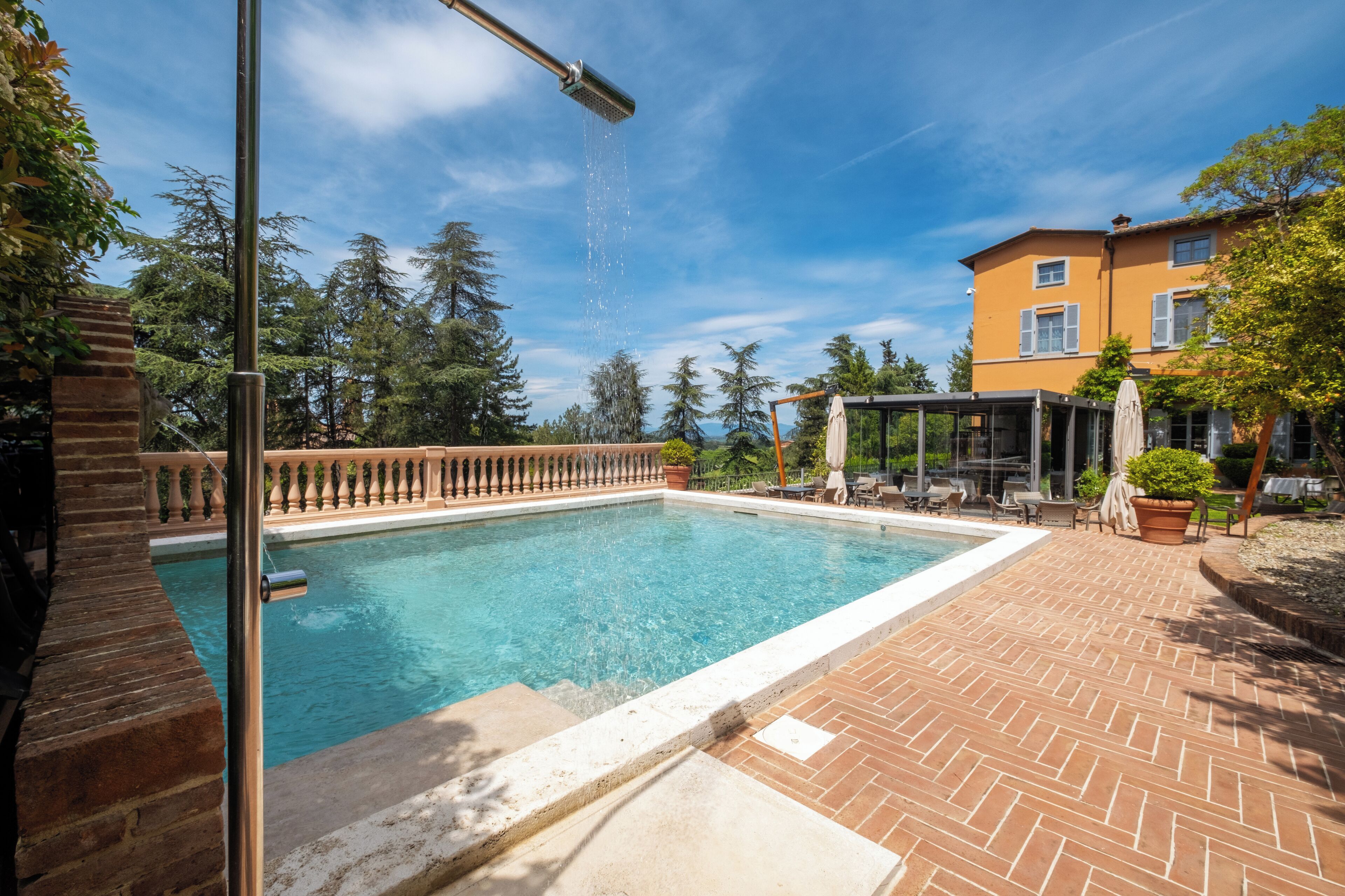 A rectangular swimming pool with a clear blue water, surrounded by a brick patio.